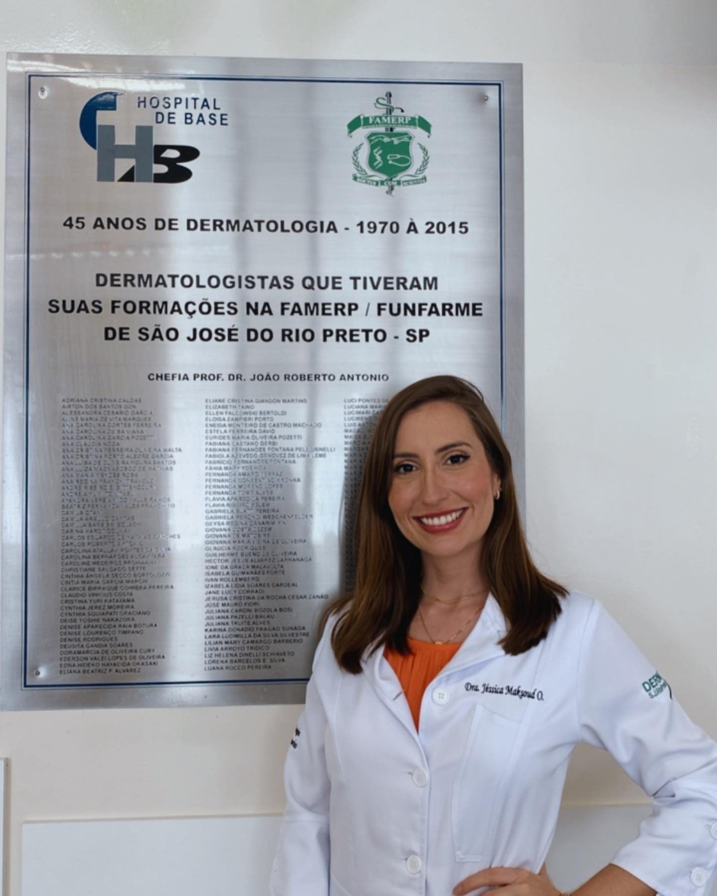 Dra. Jéssica Maksoud diante da placa de 45 anos de Dermatologia do Hospital de Base, FAMERP